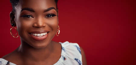 portrait of beautiful smiling african american woman on red backgroundの写真素材
