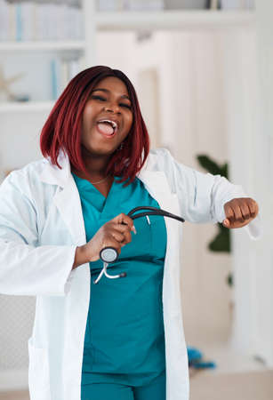 happy female doctor dancing in office, successful outcomeの写真素材