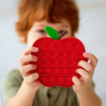 happy kid holding a vibrant sensory toy, pop it fidget toy in apple shapeの写真素材