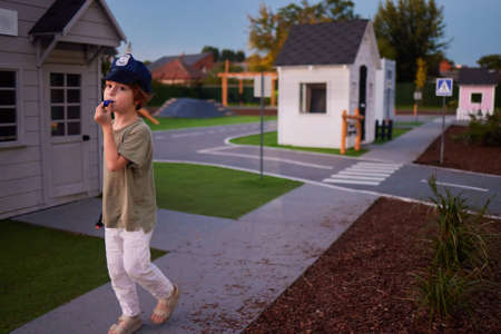 cute little boy playing the policeman, keeps order in the city , blowing a whistleの写真素材