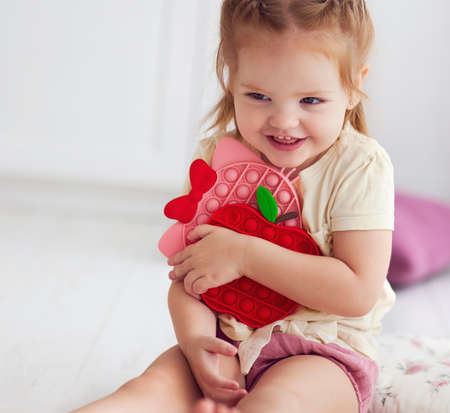 happy baby girl holding colorful sensory toys. pop it fidget toysの写真素材