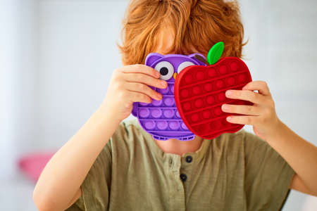redhead kid holding the vibrant sensory toys, pop it fidget toys in apple and owl shapeの写真素材