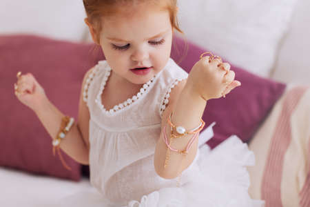 cute baby girl trying on a lot of finger rings and bracelets, bijou jewelryの写真素材