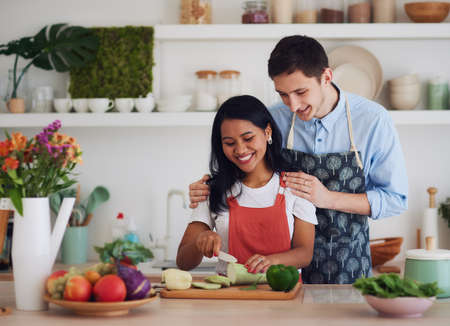 happy couple cutting vegetables on the kitchenの写真素材