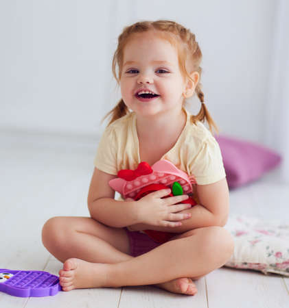happy baby girl holding colorful sensory toys. pop it fidget toysの写真素材