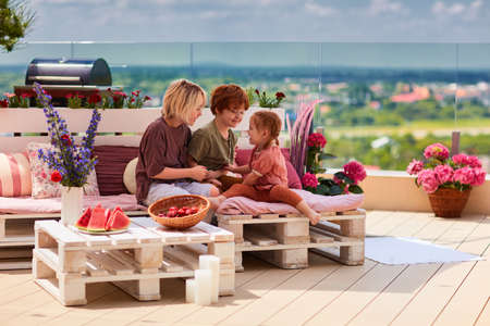 cheerful kids, siblings having fun, playing together on pallet lounge furniture at the rooftop patio on a summer dayの写真素材