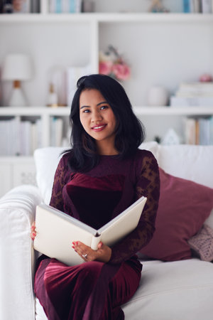 beautiful asian woman sitting on the sofa at home in classic interiorの写真素材