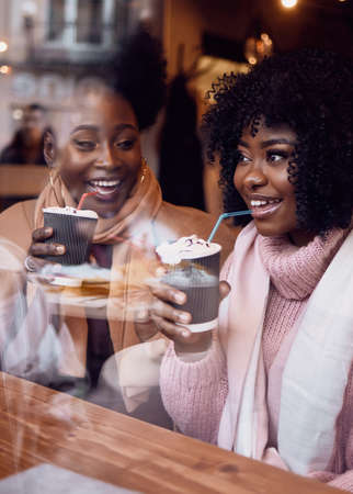 Happy Friends, Young Women Sitting in Cozy Cafe on Winter Holidaysの写真素材