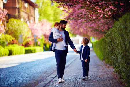 happy father with kids on the walk in spring city, paternal leaveの写真素材