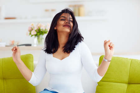 portrait of excited indian woman having fun at home. entertainment, successの写真素材