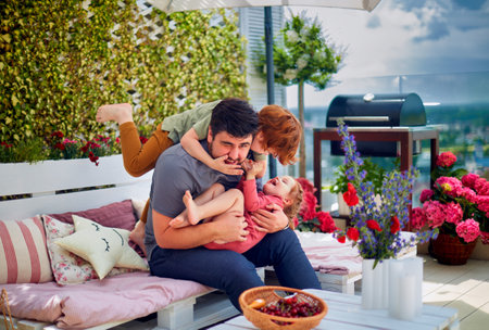 happy family, father and kids having fun, playing together on the rooftop patio on summer dayの写真素材