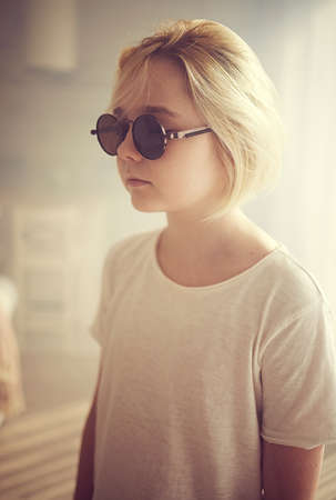 portrait of blond teenage boy standing in sunny roomの写真素材