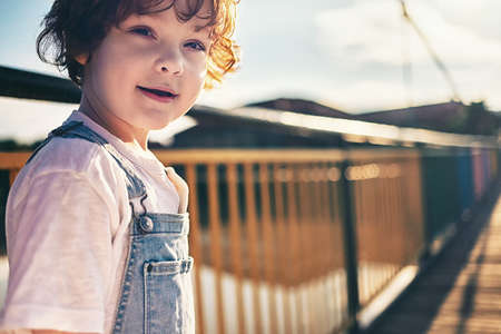 cute redhead kid walking along the bridge at the marina on summer day. warm childhood memoriesの写真素材