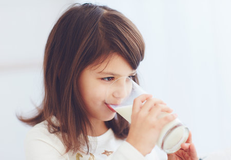 cheerful girl, cute kid drinking a glass of milkの写真素材