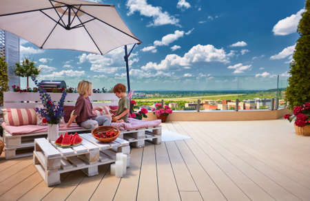 cheerful kids, siblings having fun, playing together on pallet lounge furniture at the rooftop patio on a summer dayの写真素材