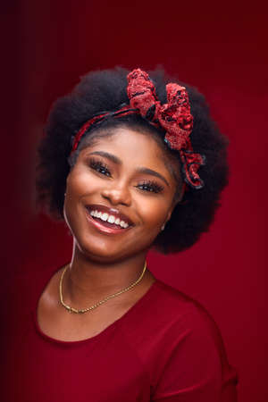 portrait of happy african american woman with headband on red backgroundの写真素材