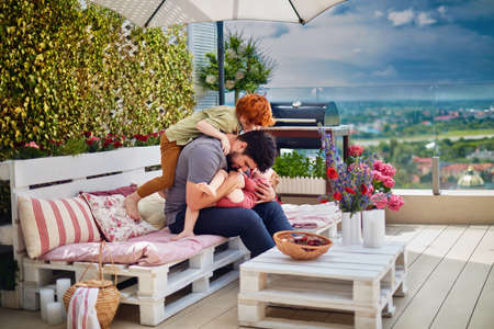 happy family, father and kids having fun, playing together on the rooftop patio on summer dayの写真素材