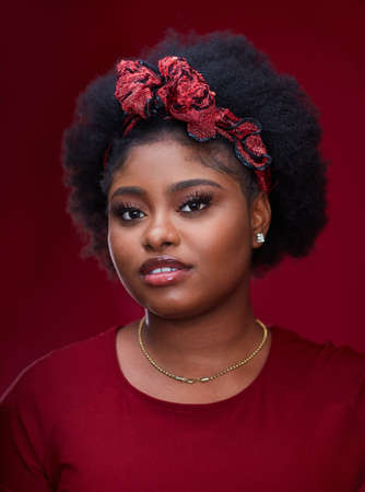portrait of beautiful african american woman with headband on red backgroundの写真素材