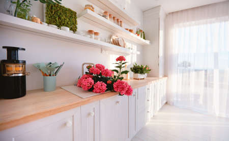 bright modern kitchen with wooden counter top and wall shelvesの写真素材