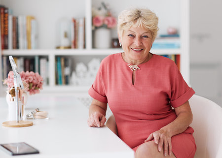 portrait of cheerful adult woman sitting at the table at homeの写真素材