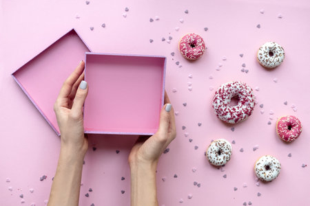 Woman hands holding empty box. Pink background with donuts.の写真素材