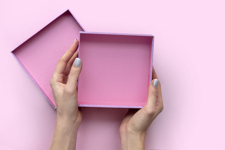 Female hands with open empty box on pink background.の写真素材