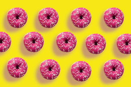 Delicious pink donuts on yellow backgroundの写真素材