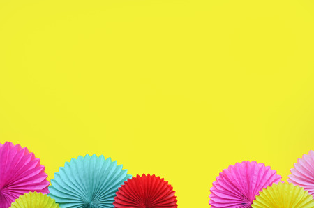 Paper flowers on yellow table top view. Festive or party background. Flat lay style. Copy space for text. Birthday greeting card.の写真素材