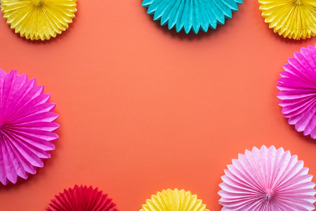 Different paper flowers on orange table top view. Festive or party background. Copy space for text. Birthday greeting card.の写真素材