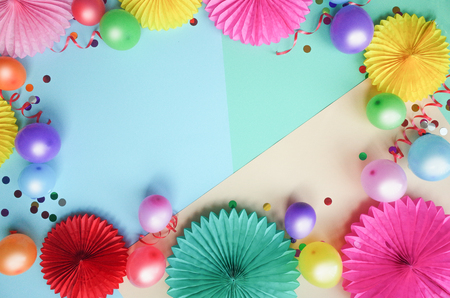 Colorful balloons and paper flowers on color table top view. Festive or party background. Flat lay style.の写真素材