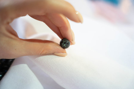One black shimmering bead held in hand on a white backgroundの写真素材