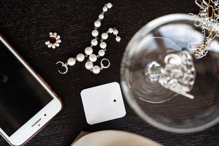 Elegant flat lay composition on black background with decorations, smartphone, glass and empty tagの写真素材