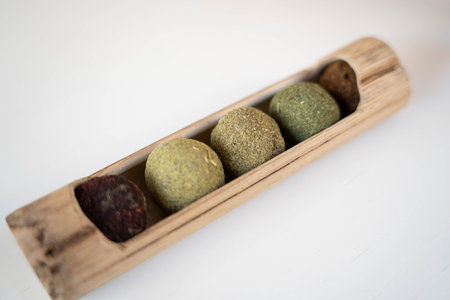 A variety of healthy energy bars or tea balls presented in a natural bamboo stand on a white backgroundの写真素材