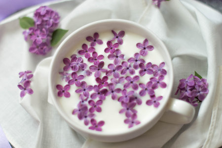 Delicate lilac flowers in a cup of milk on a white backgroundの写真素材