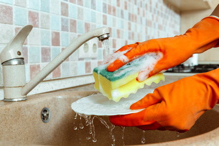 Close up hands of woman washing dishes in kitchenの写真素材