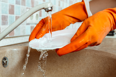 Close up hands of woman washing dishes in kitchenの写真素材