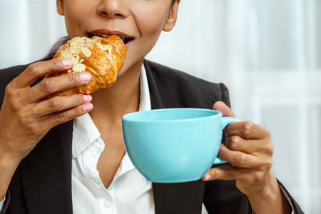 Businesswoman with cup of coffe and croissantの写真素材