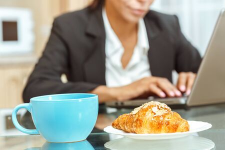 Businesswoman with cup of coffe and croissantの写真素材