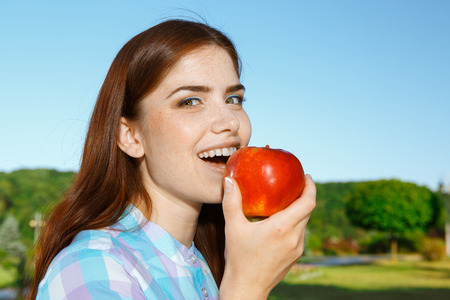 Beautiful girl eating apple in the parkの写真素材