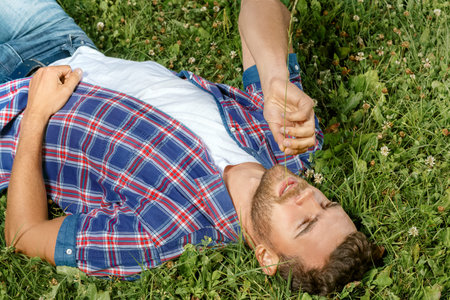 Handsome man lying on the grass in parkの写真素材