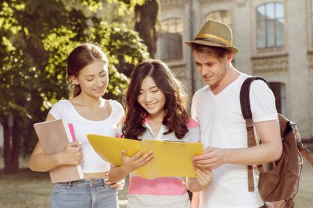 Three friends studying books on the move before examsの写真素材
