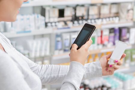 Close up of a woman taking picture of the product in drugstoreの写真素材
