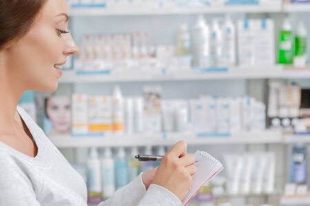 Customer making notes in drugstoreの写真素材