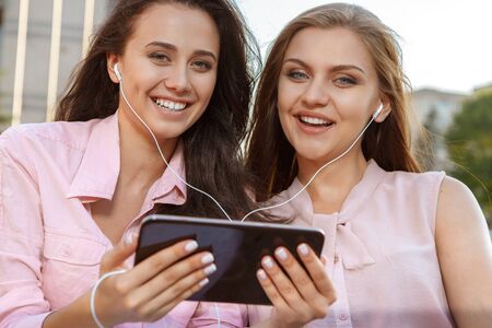 Two attractive girls listening to music on the tabletの写真素材