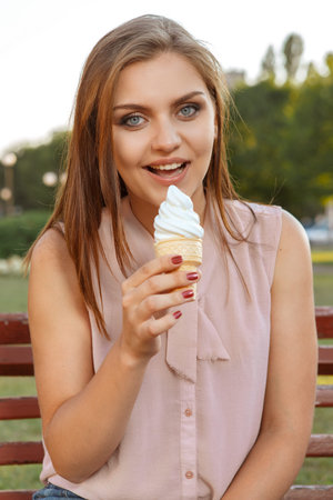 Beautiful girl eating ice cream on the bench