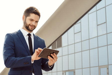 Young businessman using a digital tablet outdoorsの写真素材