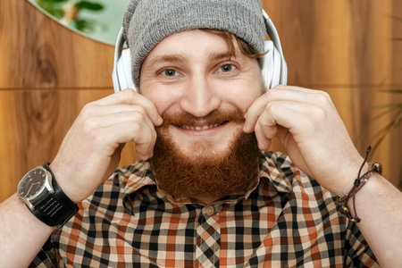 Young smiling guy straightens his mustache looking to the camera