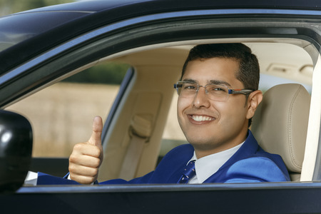 Handsome businessman showing thumbs up while sitting in the carの写真素材