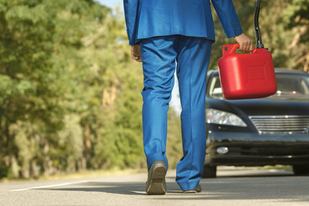Businessman going to the car with jerrycan to fill itの写真素材