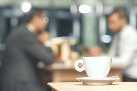 Cup of coffee on a table with a business partners in the backgroundの写真素材